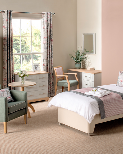 Neatly arranged bedroom with furniture including a bed, chair, and wardrobe.